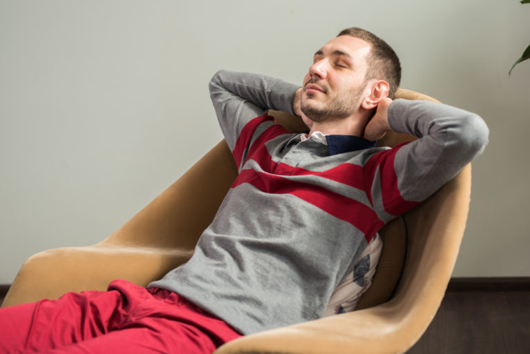 A man sitting in a relaxed position in a chair.