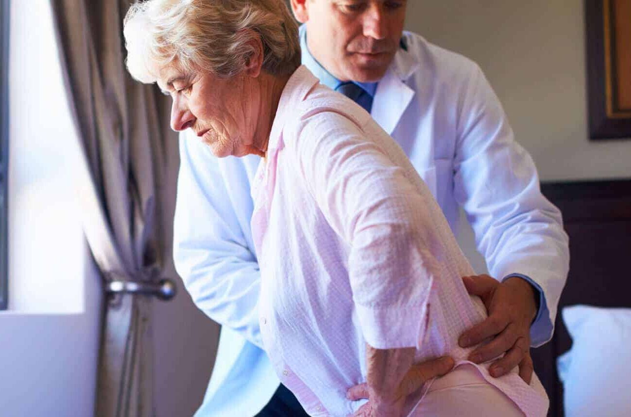 Doctor helps a woman who is in pain to her feet.