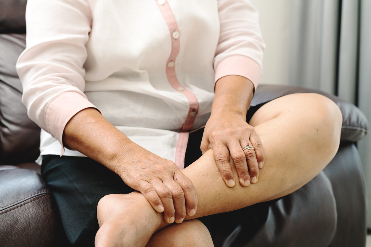 A woman holding her calf as she has leg cramp.